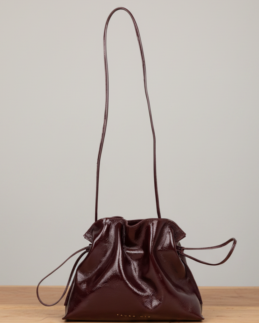 Antonia Slouchy Charol Vino — Mesa madera, fondo gris neutro